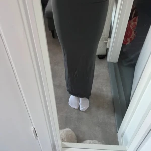 Grå långkjol från H&M - Säljer en stilren grå långkjol från H&M. Kjolen har en tight passform. Den är lite nopprig över ungefär hela kjolen (se sista bilden) men tycker inte det syns när man har på sig den.