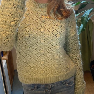 Ljusgrön stickad tröja - Säljer en mysig ljusgrön stickad tröja med ett vackert mönster. Tröjan har långa ärmar och ribbstickade muddar vid ärmslut och nederkant. Perfekt för kyliga dagar! Jättefin verkligen och speciellt till sommaren över en tshirt!
