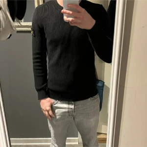 Stone Island tröja - Säljer en stilren svart ribbad tröja från Stone Island. Storlek S sparsamt använd 