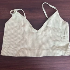 Beige ribbad linnetopp från Pieces - Säljer en stilren beige ribbad linnetopp från Pieces. Toppen har smala axelband och en v-ringad design som ger en snygg look. Perfekt för varma dagar eller som ett lager under en jacka.