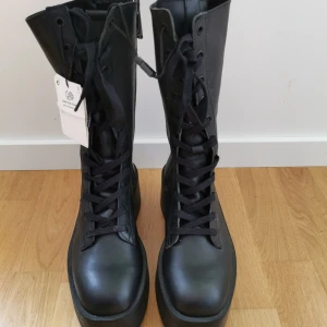 Svarta boots med platåsula från Zara - Snygga svarta boots från Zara med hög platåsula och snörning. De har en dragkedja på sidan för enkel på- och avtagning. Perfekta för att ge lite extra höjd och stil till din outfit. Oanvända. 