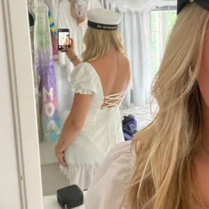 Vit klänning med volangdetaljer - Säljer en super fin studentklänning med öppen rygg. Klänningen har snörning i ryggen så det går att justerba passform. Perfekt för sommaren eller för student/avslutning. Endast använd en gång, dagen innan studenten.🙌🌷💥