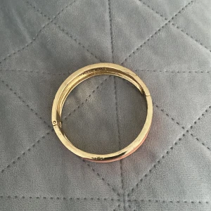 Guldarmband från IsaDora - Elegant guldarmband från IsaDora med en stilren design. Armbandet har en mjuk rosa yta som ger en fin kontrast till den gyllene färgen. Perfekt för att lägga till en touch av lyx till din outfit.