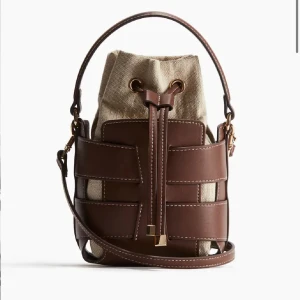 Brun och beige axelväska - Snygg axelväska i brunt och beige med ett unikt designmönster. Väskan har en praktisk snörning och är perfekt för att bära med sig det nödvändigaste. Tillverkad i syntetmaterial. Helt ny, prislapp kvar. Skriv ifall du är intresserad 🌟💛✨ ANVÄND INTE INSTABOX💛