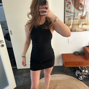 Svart ärmlös klänning - Snygg svart ärmlös klänning med en tight passform. Perfekt för en kväll ute eller en speciell tillställning. Klänningen har en enkel och stilren design som framhäver figuren.