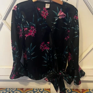 Svart blus med rosa blommönster från UNIQ YOUNG - Säljer en svart blus med blommor på, blusen har ett mljukt siden material och är från UNIQ YOUNG🌸 skriv till mig för mer info och pris kan diskuteras🌸