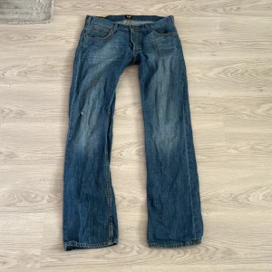 Blå jeans från Lee - Säljer ett par klassiska blå jeans från Lee. De har en rak passform och är tillverkade i slitstarkt denim. Byxorna har fyra fickor och en knappgylf. Perfekta för en avslappnad stil.
