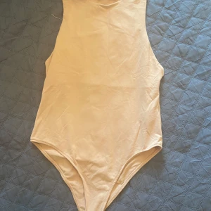 Beige ärmlös bodysuit - Säljer en stilren beige bodysuit med ärmlös design. Perfekt för lager-på-lager eller att bära som den är. Mjukt och stretchigt material för en bekväm passform.