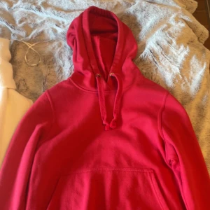Röd hoodie - Säljer en klassisk röd hoodie med justerbara snören i huvan och en stor magficka framtill. Perfekt för en avslappnad stil och bekväm att bära under kyligare dagar.💓
