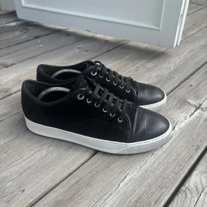 Lanvins uk 8 passar 42/43 - Snygga svarta sneakers med vit sula och rund tå. Skorna har snörning och en stilren design som passar perfekt till vardags. Tillverkade i skinn för en hållbar och bekväm känsla. Bra skick utöver lite repor på cap toen inget tillkommer vid köp utöver skorna kvitto finns ej, priset går att diskutera vid snabb affär!