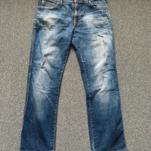 Blå jeans från Nudie Jeans - Säljer ett par klassiska blå jeans från Nudie Jeans i storlek 33/32. De har en snygg tvättad look med ljusare partier och traditionella fem fickor. Perfekta för en avslappnad stil.