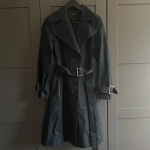 Svart trenchcoat - Svart trenchcoat från Tessie i storlek S. Upplever den dock som stor för att vara i storlek S, passar M skulle jag säga.