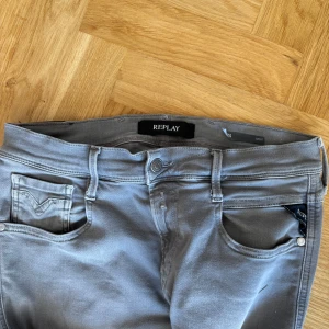 Grå jeans från Replay - Snygga grå jeans från Replay med klassisk femficksdesign och knappgylf. De har en stilren look med diskreta sömmar och en bekväm passform. Perfekta för en avslappnad stil. W30 L30
