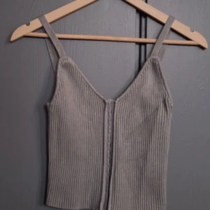 fest topps - Snygg grå ribbad linnetopp med smala axelband och v-ringning. Perfekt för en stilren och enkel look. Passar bra till både jeans och kjol.