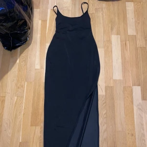 Svart långklänning med snörning - Elegant svart långklänning med smala axelband och snörning i ryggen. Perfekt för en stilren look.