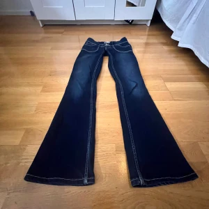 Lowwaist jeans - Snygga jättelowwaist mörkblå bootcut jeans från Levis med kontrasterande vita sömmar och dubbla knappar i midjan. Klassiska femficksdesign med märkets logga på bakfickan. Perfekta för en avslappnad stil. Jättebra skick, förutom en liten defekt på ena bakfickan, se bild 4. Innerbenslängden är 79cm och midjemåttet är 35cm men tyget är stretchigt så kan passa upp mot 37cm❤️