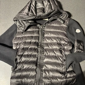  Moncler cardigan  - Snygg svart dunväst från Moncler med huva och dragkedja. Har inga ska dit och är typ som ny, storlek M men passar på S
