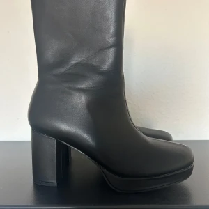 Svarta stövletter - Snygga svarta stövletter i skinn från NLY Shoes. De har en hög, fyrkantig klack och dragkedja på sidan för enkel på- och avtagning. Perfekta för både vardag och fest! Använt en gång.
