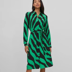 Grön och svart klänning från Vila - Snygg grön och svart skjortklänning från Vila med zebramönster. Klänningen har långa ärmar och knappar framtill samt ett knytband i midjan för en smickrande passform. Fint skick utan anmärkningar 
