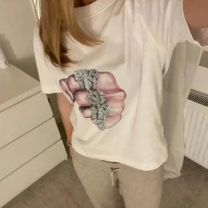 Vit t-shirt med tryck - Säljer en vit t-shirt med ett coolt tryck av en hand. Tjejen jag köpte den av här på Plick har gjort trycket själv som är skit snyggt! Har en liten defekt vid armhålorna men som inte snyns på💗💗