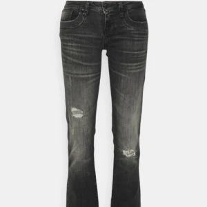 Svarta jeans med slitningar från ltb - Snygga svarta jeans från Ltb med slitningar på benen för en trendig look. De har en bootcut-stil och är perfekta för en avslappnad stil. Jeansen har en klassisk femficksdesign och knappar i midjan. Mycket lågmidjade! Uppsprättade längst ner för min längd men går självklart att få tillbaka igen! Storlek: W28 L34