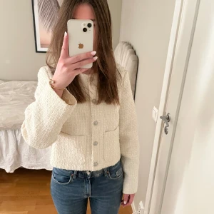 Vit tröja - Säljer en stilren vit tröja från H&M med knappar framtill. Tröjan har en klassisk design med rund hals och två fickor. Perfekt för en chic look!