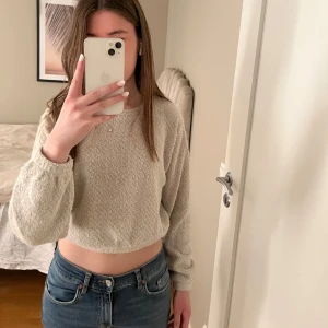 Beige stickad croppad tröja - Säljer en mysig beige stickad tröja med croppad passform. Tröjan har långa ärmar och en rund halsringning. Perfekt för en avslappnad stil.