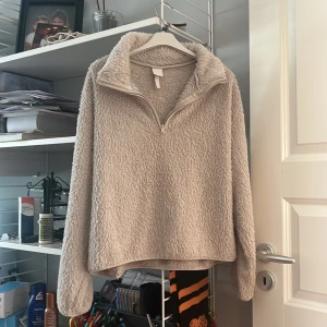 Beige fleece tröja från H&M - Mysig beige fleece tröja från H&M med dragkedja vid halsen. Perfekt för kyliga dagar med sin fluffiga och varma design. Tröjan har långa ärmar och en avslappnad passform. Denna är verkligen jätte skön. Storleken är i xs men själv har jag s men den passade mig jätte fint. 