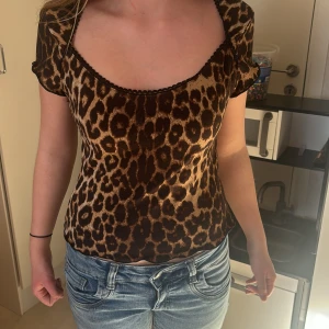 Leopardmönstrad topp - Säljer en snygg leopardmönstrad topp med korta ärmar och rund halsringning. Perfekt för att ge din outfit en vild touch. Toppen är i ett mjukt och stretchigt material.