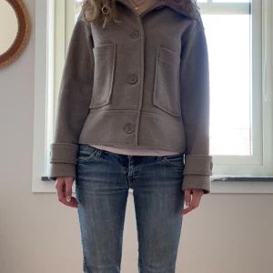 Kort beige kappa från Kappahl - Superfin kort beige kappa som jag knappt använder längre då jag har en annan jacka. Väldigt bra skick men använd en del. Köpt för 899 på Kappahl. 