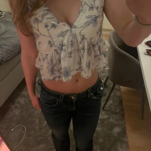 Blommig vit och blå blus - Säljer en söt blommig blus i vitt och blått med volanger och v-ringning.🫶