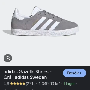 Grå Adidas Gazelle Sneakers - Säljer ett par klassiska grå Adidas Gazelle sneakers med vita detaljer och snörning. Skorna har en stilren design med de ikoniska tre ränderna på sidan och en bekväm passform. Dem är absolut andvända men är fortfarande i ett relativt bra skick och går säkert att tvätta! Finns en tydlig fläck i skon men inget som märks av!
