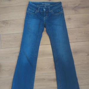 Blå jeans från American Eagle - Snygga blå jeans från American Eagle med bootcut-stil. De har en klassisk femficksdesign och knappar bak på fickorna. Lite slitna längst ner. Står att de är storlek 2REG men skulle gissa typ 29 midja, 32 längd.