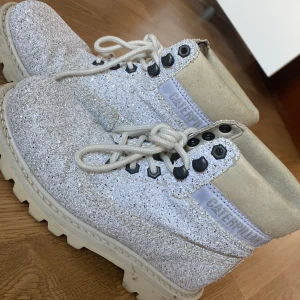 Glittriga boots från Caterpillar - Säljer ett par glittriga boots från Caterpillar i storlek 37. Skorna har en robust design med snörning och en bekväm sula. Perfekta för att ge lite extra bling till din outfit!