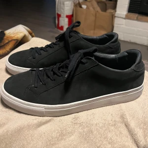 Svarta sneakers med vit sula - Snygga svarta sneakers med vit sula och snörning. Perfekta för en stilren look. Tillverkade i ett material som liknar mocka, vilket ger en elegant touch. Strlk 47. Ord pris 1440 säljes nu för 800 men pris går att diskuteras