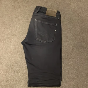 Blåa jeans från Replay - Snygga blåa jeans från Replay, modell Anbass. De har en klassisk femficksdesign med en diskret logga på bakfickan. Perfekta för en stilren look.