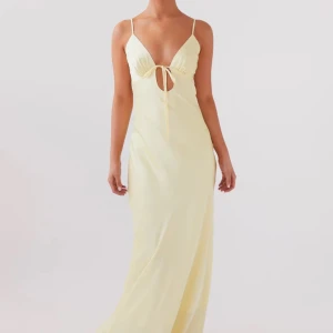  Långklänning i satin från Peppermayo - Ljusgul långklänning i satin. Smala axelband och knytning framtill. Klänningen har en öppen rygg med knytning där bak vilken gör att storleken är justerbar. Aldrig använd med lapparna kvar.💗