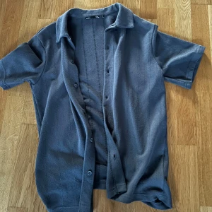 Mörkgrön kortärmad skjorta från 157 - Snygg mörkgrön  kortärmad skjorta från 157. Skjortan har en klassisk krage och knappar framtill. Perfekt för en avslappnad stil.