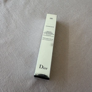 Diorshow Mascara 090 Pro Black - Säljer en Diorshow Mascara i färgen 090 Pro Black. Denna mascara ger volym och definition till dina fransar med en intensiv svart nyans. Förpackningen är elegant med Dior-logotypen och en dekorativ silverdetalj. Perfekt för att framhäva ögonen med en dramatisk look.                                                                                  Aldrig använd! Öppnad bara för ta bild på borsten⚠️⚠️