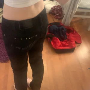 Svarta jeans med nitar - Snygga svarta jeans med coola nitar på bakfickorna. De har en klassisk femficksdesign och en dekorativ läderpatch med mönster. Perfekta för en edgy look!