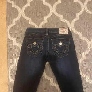 True religion mörkblå jeans med broderade fickor - Snygga mörkblå jeans med unika broderade detaljer på bakfickorna. Byxorna har en klassisk femficksdesign och en bekväm passform. Perfekta för en stilren look. Obs, jeansen har en liten vit missfärgning på höger benet och lite på vänster men märks inte och är inget man tänkte på. Priset går absolut diskuteras. 