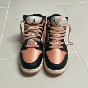 Nike Air Jordans i svart och rosa - Snygga Nike Air Jordans i en cool kombination av svart, rosa och vitt. Skorna har en klassisk hög design med snörning och den ikoniska loggan på plösen. Perfekta för dig som vill ha en stilren och sportig look.