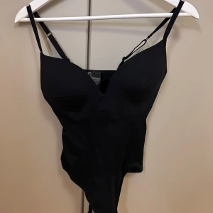 Slutsålda HM,  bodysuit med justerbara axelband - Snygg svart bodysuit med justerbara axelband och tryckknappar i grenen.
