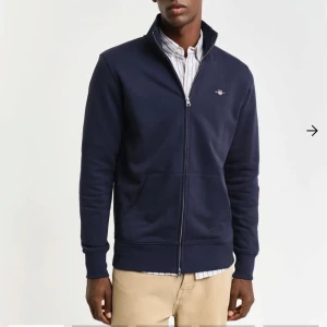 Mörkblå fullzip från GANT - Säljer en snygg mörkblå fullzip från GANT i oanvänt skick. Köpt för 1500kr.