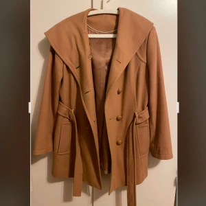 Beige kappa med bälte - Storlek 38/40, använd sparsamt och endast ett fåtal gånger! Den senaste bilden stämmer mest överens med kappans färg :)