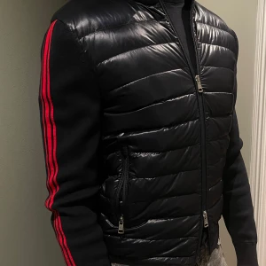 Marinblå cardigan från Moncler - Tja, säljer denna stilrena zip cardigan från Moncler i otroligt bra skick, självklart är den äkta (kvitto finns!). Jackan har en dragkedja framtill och är tillverkad i ett glansigt syntetmaterial. Säljes inte längre.