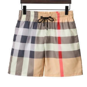 Rutig badshorts från Burberry - Snygga badshorts från Burberry med klassiskt rutigt mönster i beige, grå och röd. De har en elastisk midja med svart snörning för justerbar passform. Perfekta för sommarens stranddagar! Riktigt stil rena burbbery shorts passar till alla outfits skriv för funderingar 🤔 tveka inte ens på att skiva 😉