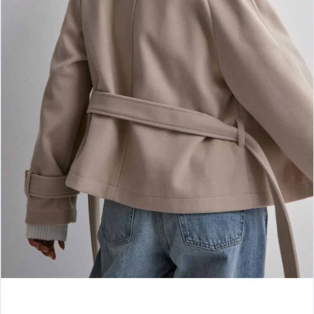 Snygg beige kappa från Nelly med knytbälte i midjan och klassisk krage. Jackan har långa ärmar med justerbara spännen vid ärmsluten. Perfekt för en stilren look, använt bara 3 gånger helt ny . Takit.