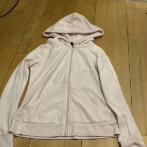 Ljusrosa hoodie från Gina Tricot - Mysig ljusrosa hoodie från Gina Tricot med dragkedja och huva. Perfekt för en avslappnad stil. Den har långa ärmar och praktiska fickor framtill. Sitter dock mer som en xs än M 