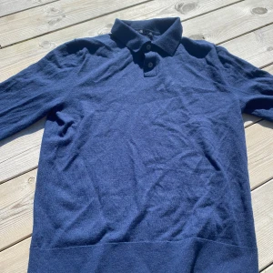 Mörkblå pikétröja från Zara - Säljer en stilren mörkblå pikétröja från Zara. Tröjan har långa ärmar och en klassisk krage med knappar. Perfekt för en avslappnad men ändå snygg look.